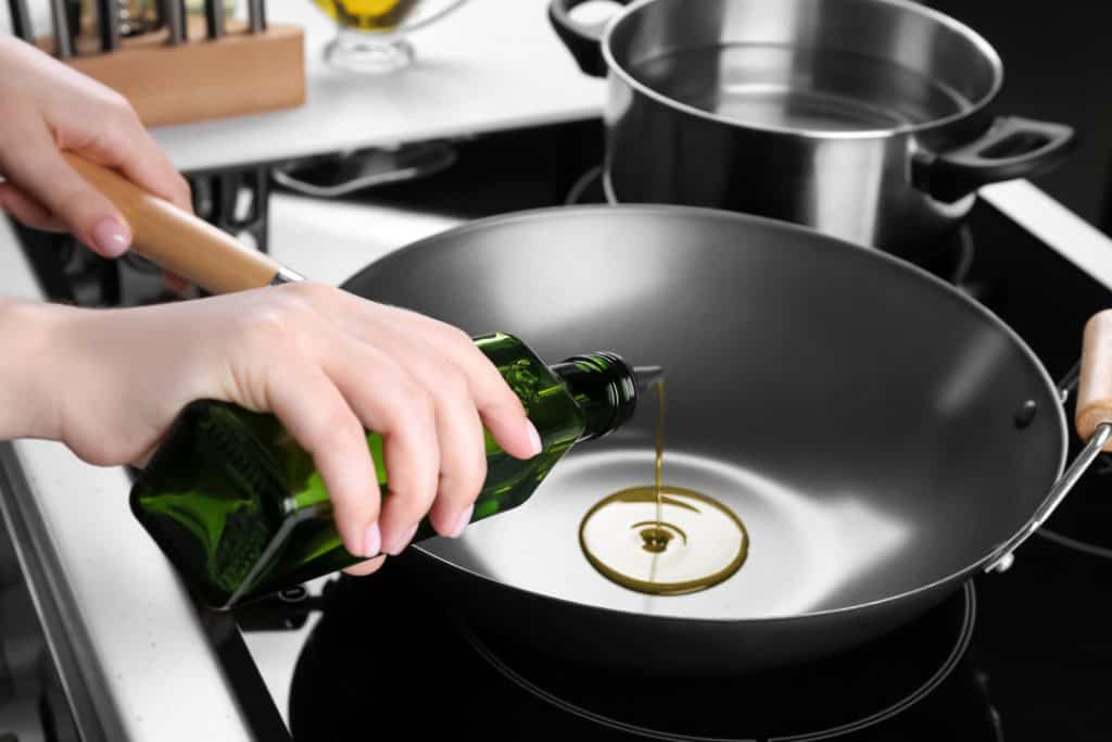 man pouring oil in a wok