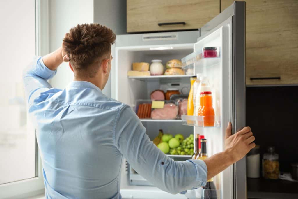 man unsure to close fridge