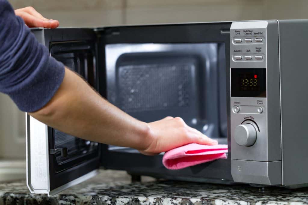 man cleaning microwave
