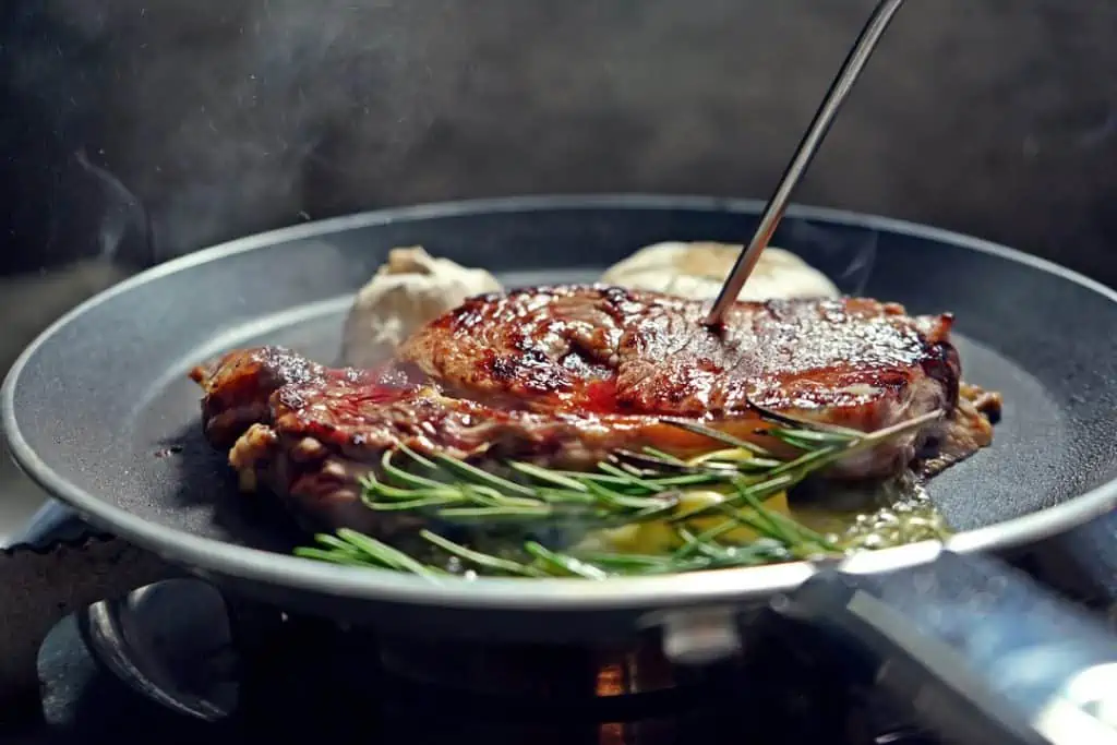man searing steak on non-stick pan