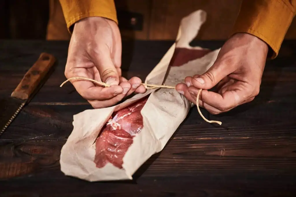 man tying knot around butcher paper